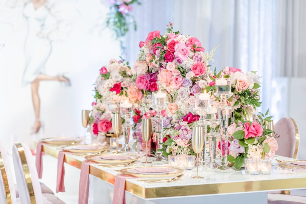 Luxury tablescape with dusty pink napkins, a gold and white table and circular flower centerpieces