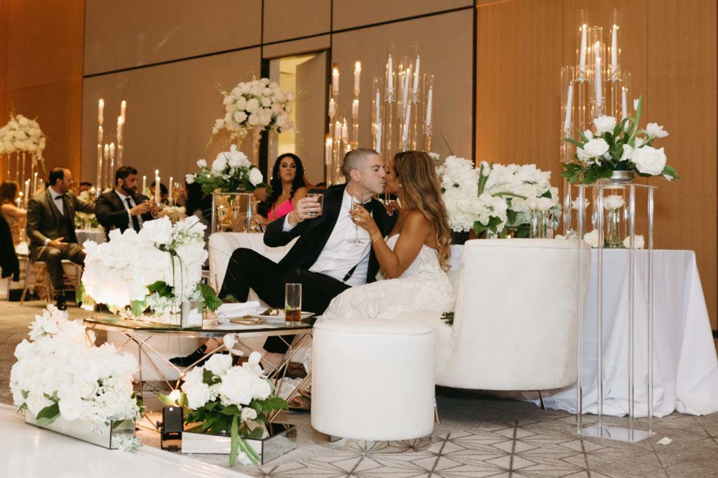Bride and groom kissing while sitting on a white couch