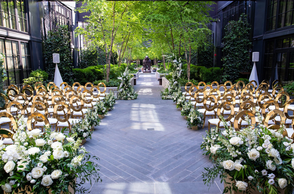 Wedding Ceremony with gold chairs and white flowers with greenery
