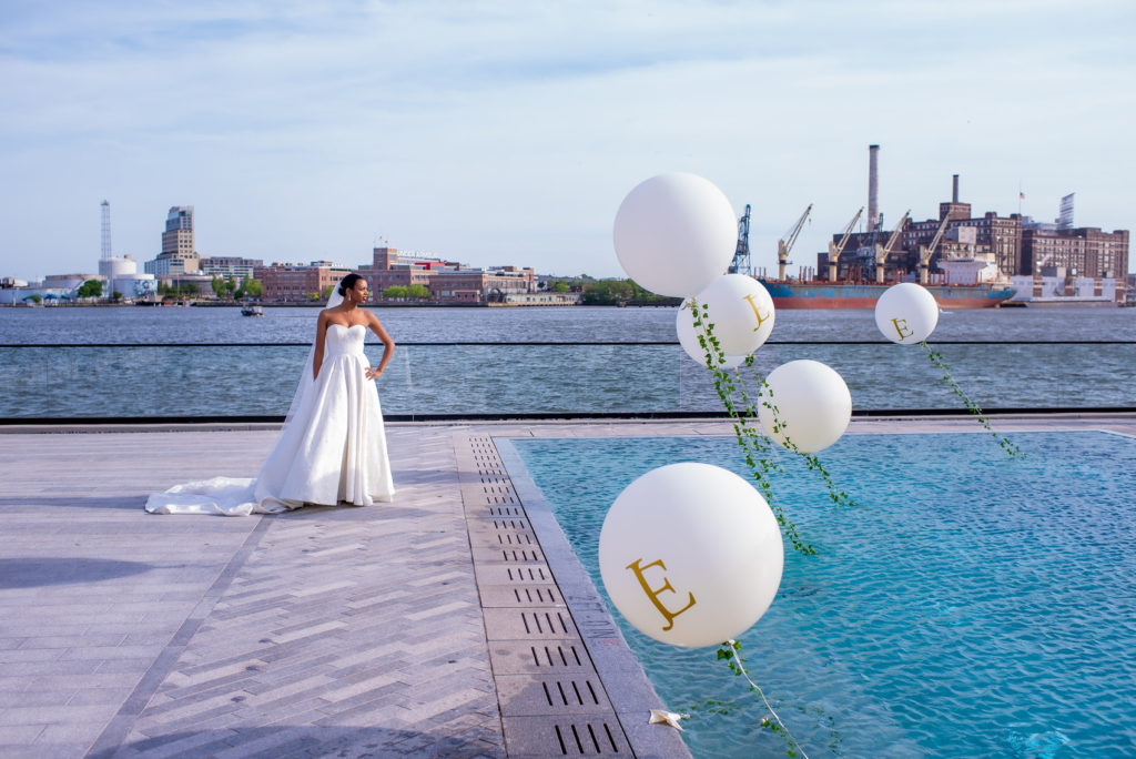 Bride posing by a pool with wedding balloon decor