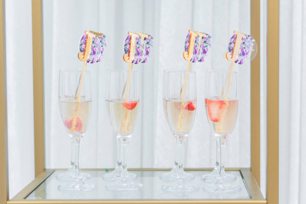 Signature cocktail for bridal shower, champagne flutes with champagne, a strawberry, and a personalized monogram stirrer.