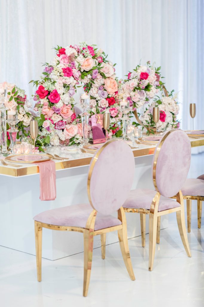 Dusty pink velvet chairs and unique circular centerpieces used in a luxury bridal shower table setting.