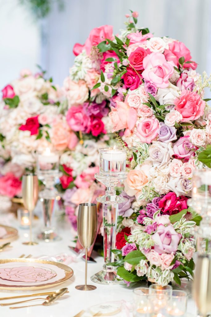 Pink white and purple rose bridal shower centerpiece with candles and gold champagne flutes