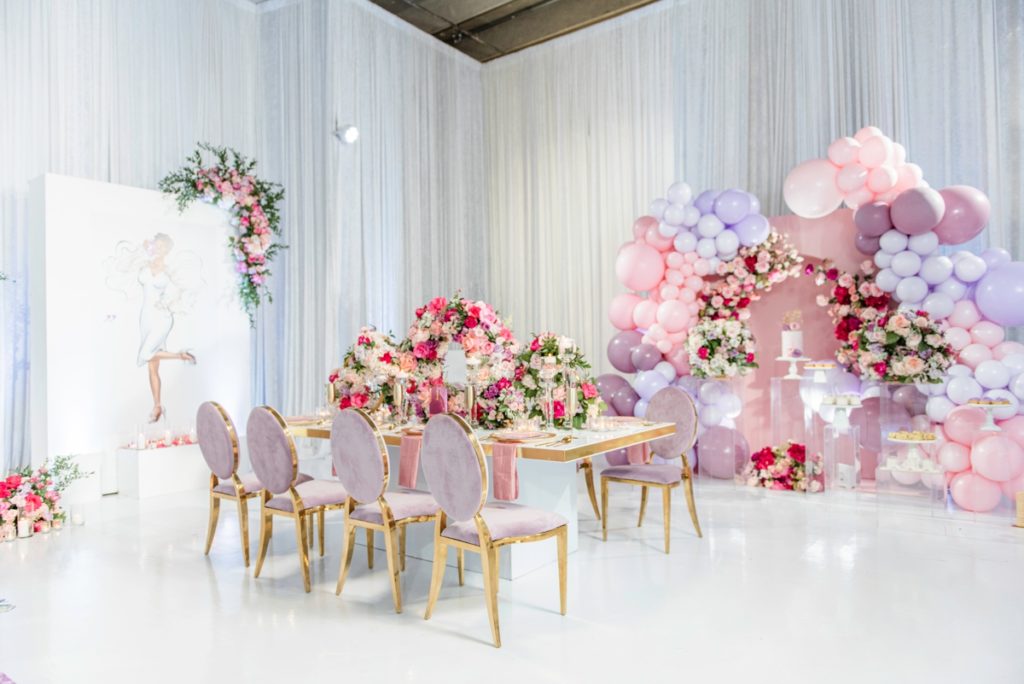 Pink bridal shower decor including a luxury flower tablescape , balloon arch and bridal shower cake display