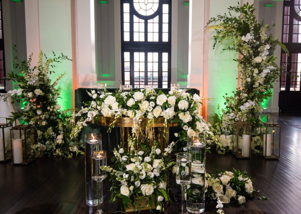 Cascading white flowers, clear tall votives with floating candles at the sweetheart table