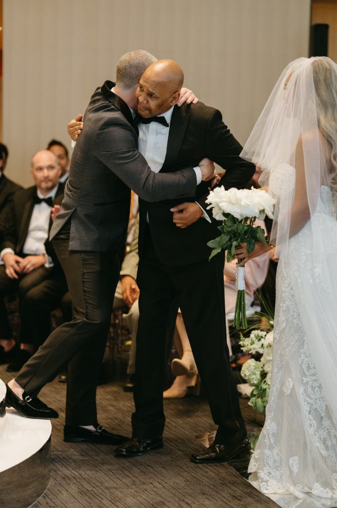 Groom hugging father of the bride at ceremony