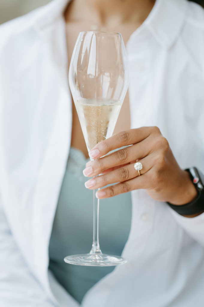 Bride holding a champagne glass with engagement ring showing