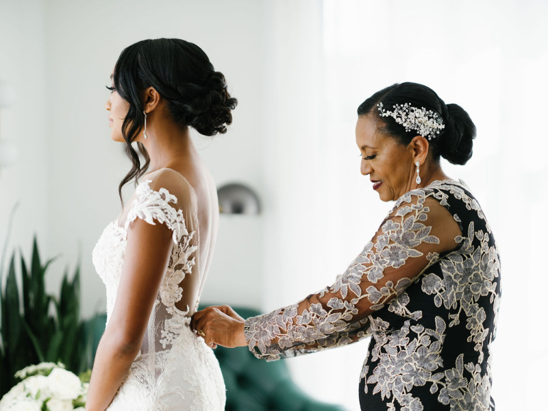 brides mom helping her into her wedding dress