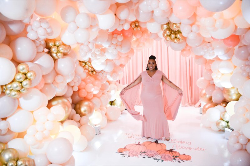 maternity photos at girl baby shower underneath balloon archway