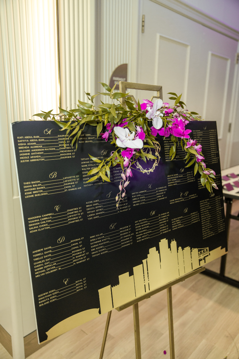 black and gold seating chart with purple white and green florals