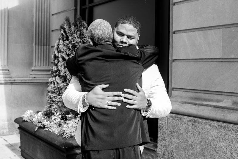 groom hugging his dad black and white wedding photo