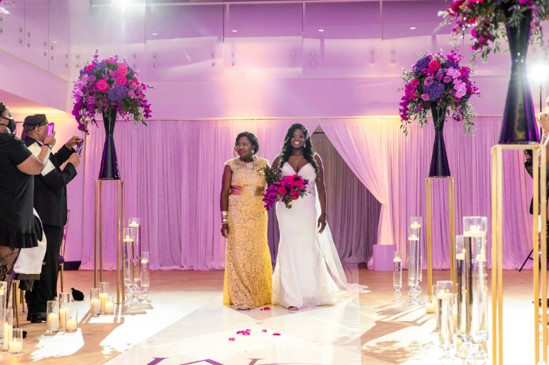 bride walking down the aisle with pink and purple bouquet