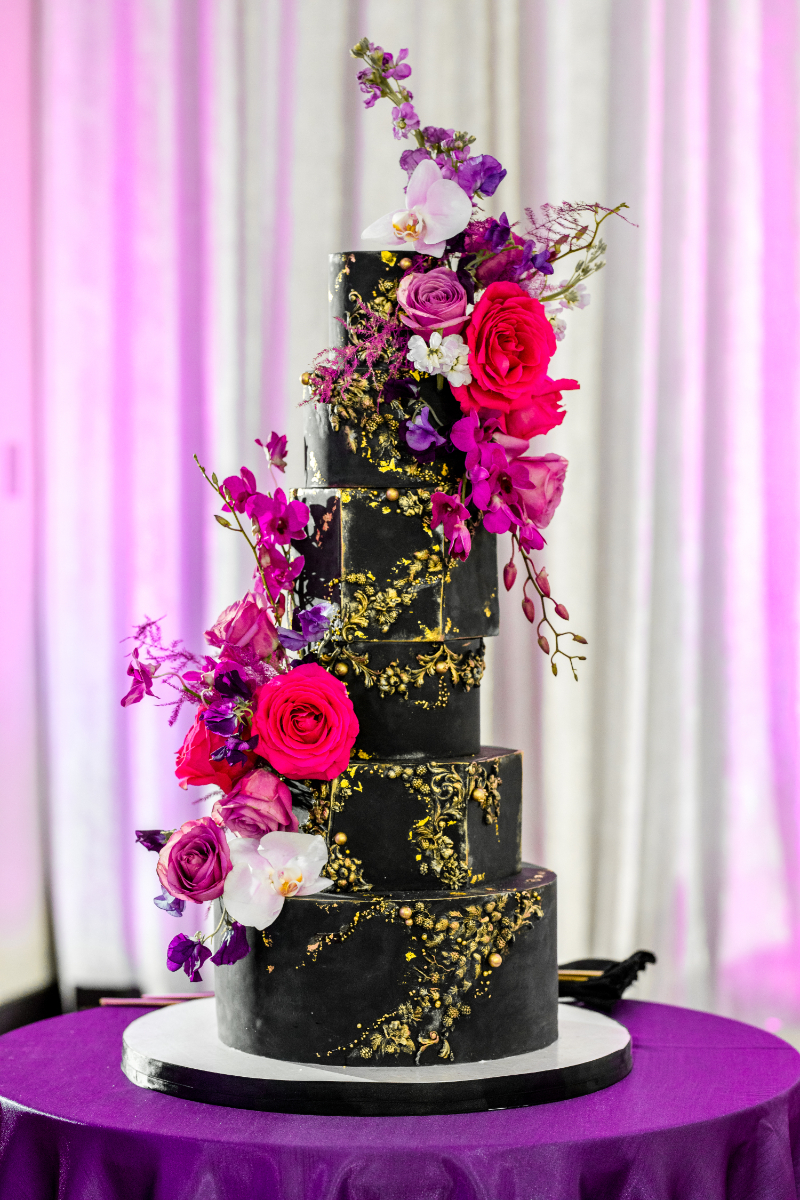 glamorous black and gold wedding cake with bright flowers