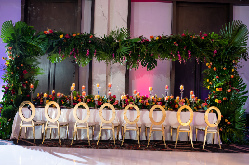 gold chairs and tropical leaves, candles, and bright florals