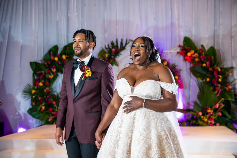 bride and groom see their wedding reception decor and smile