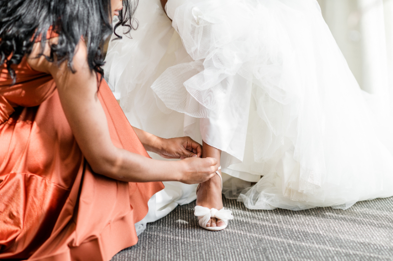 BRIDESMAID HELPING BRIDE WITH HER SHOES