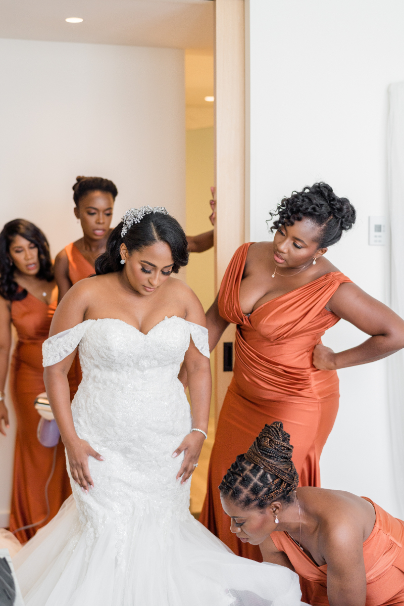 BRIDESMAIDS HELPING BRIDE WITH HER DRESS