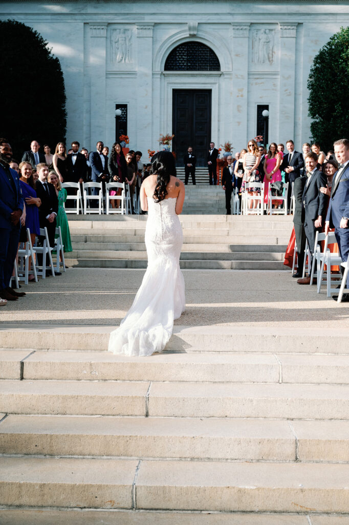 Bride walks down aisle toward her groom at the end of the aisle during this  Potomac View Terrace wedding.