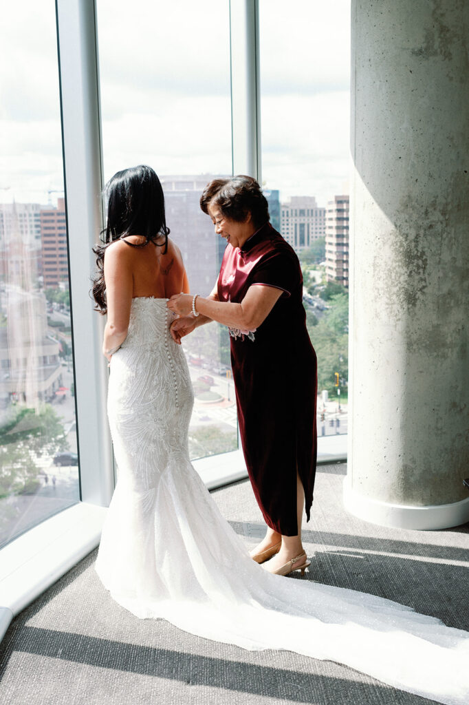 Bride gets zipped into her wedding dress by her mother as she overlooks DC from the Potomac View Terrace.