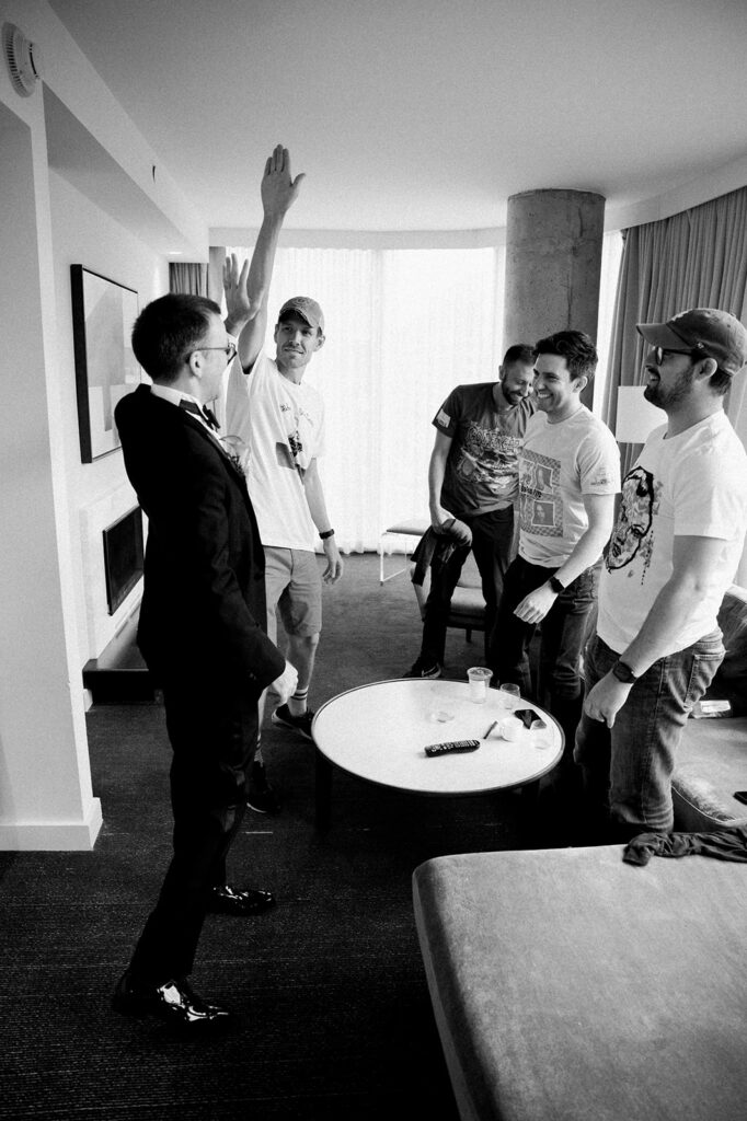 Groom high-fives groomsmen after finishing the final details of getting ready for his wedding day.