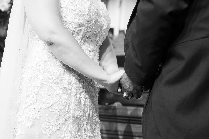 Close up of bride and groom holding hands during wedding ceremony.