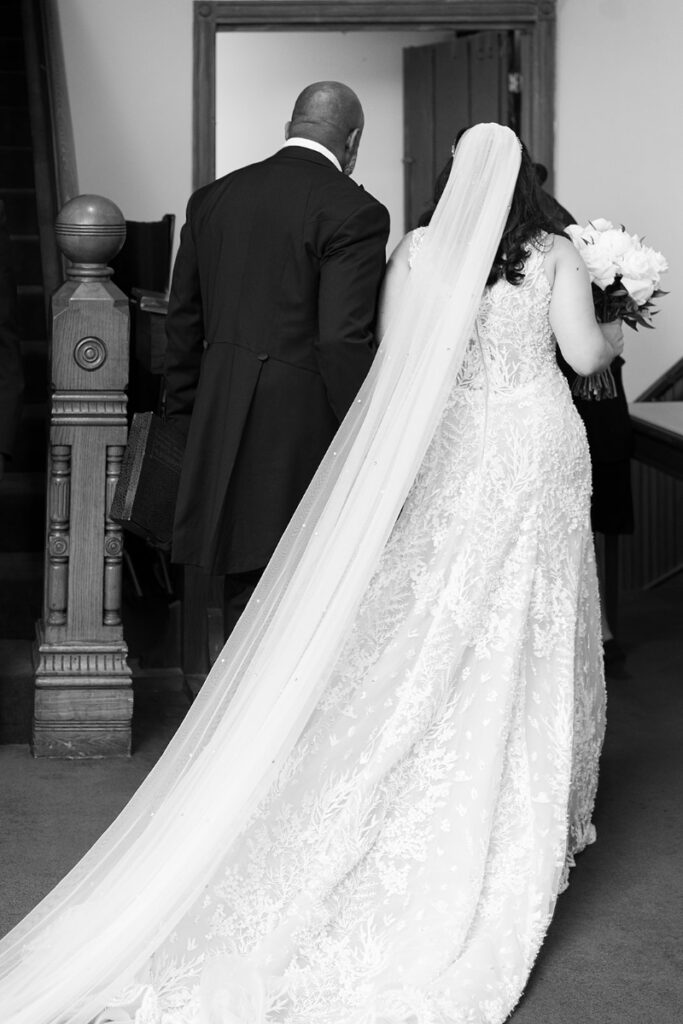 Detail shot of the back of dress as bride walks down the aisle with her father.