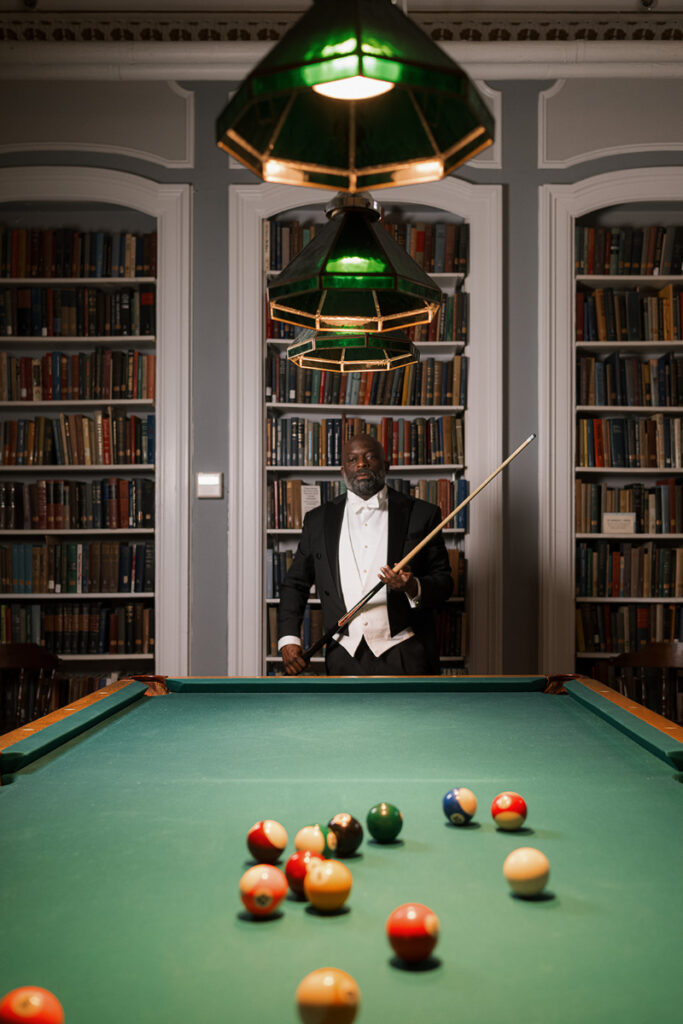 Groom poses for portrait at the end of a pool table.