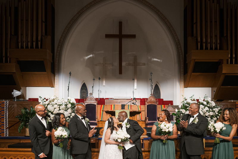Bride and groom share first kiss during wedding ceremony.