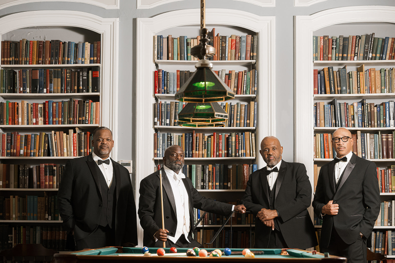 Groom poses with groomsmen at the end of a pool table.