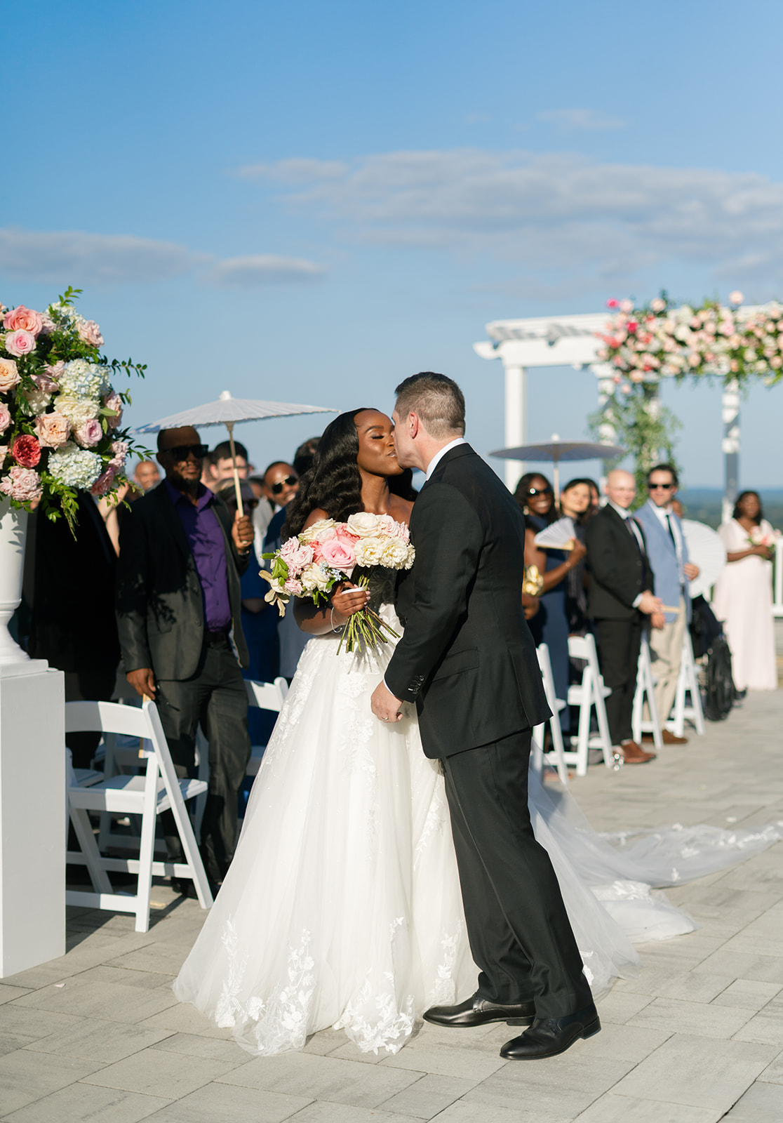 Bride and groom share kiss at the end of ceremony aisle of their mansion wedding.