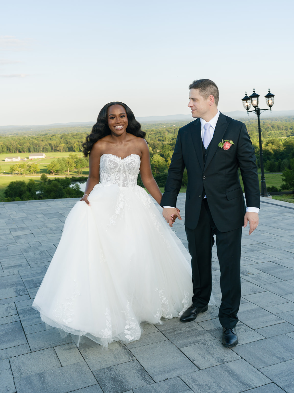 Bride and groom walk together hand in hand after exchanging vows at their mansion wedding.