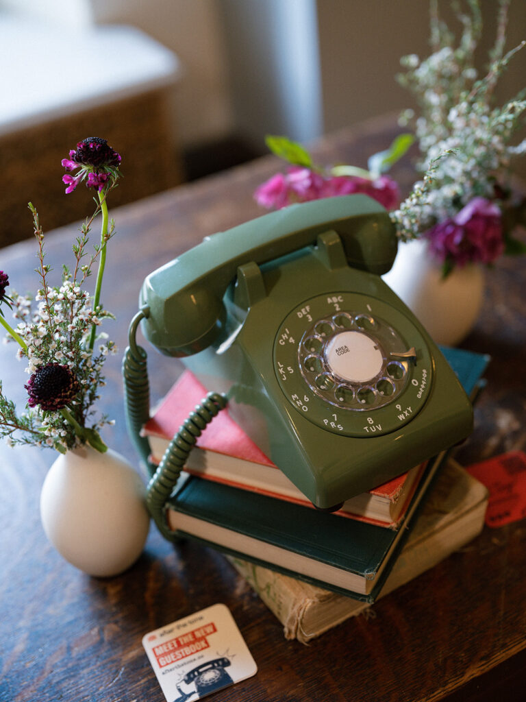 Vintage rotary phone guest book displayed on stacked books at a historic library wedding venue.