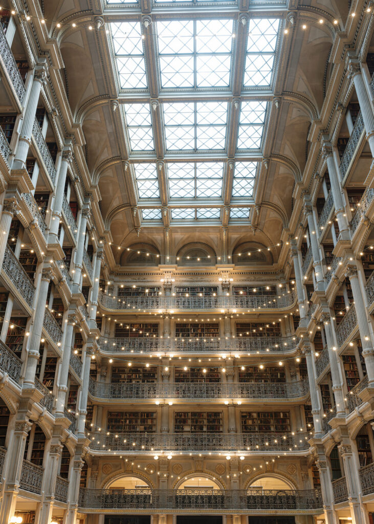 Historic library wedding venue featuring the grand architecture and illuminated book stacks inside the George Peabody Library.